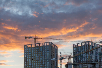 construction cranes against the background of bright evening clouds	