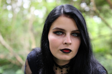 Fototapeta premium Portrait of spooky young woman with long black hair, blue eyes and dark makeup