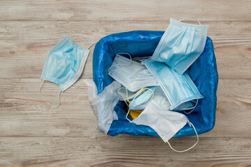 Used and contaminated surgical masks in the waste bin.