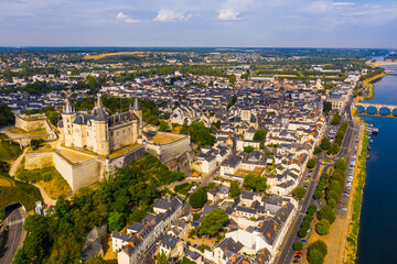 Drone view of ancient Chateau de Saumur and church of St. Peter with cityscape on background on sunny summer day, France
