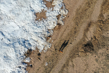 A couple, a man and a woman walk near a frozen lake. Silhouettes. Aerial view from a drone
