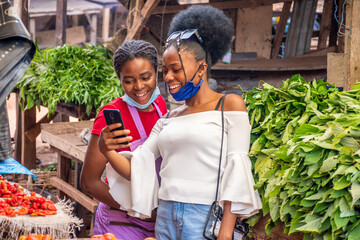 customer in a market showing a trader something exciting on her phone