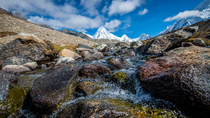 Landscape with a clear mountain river with rocks on the background of a snowy mountain in the Himalayas