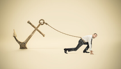 businessman in starting position tied to a big anchor