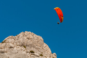 a man flies on a paraglider over a mountain in greenery and a blue sea