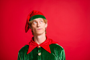 Photo of funny guy interested look up empty space wear santa elf green costume cap red color...