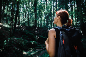 Female hiker with backpack enjoying hiking in forest.