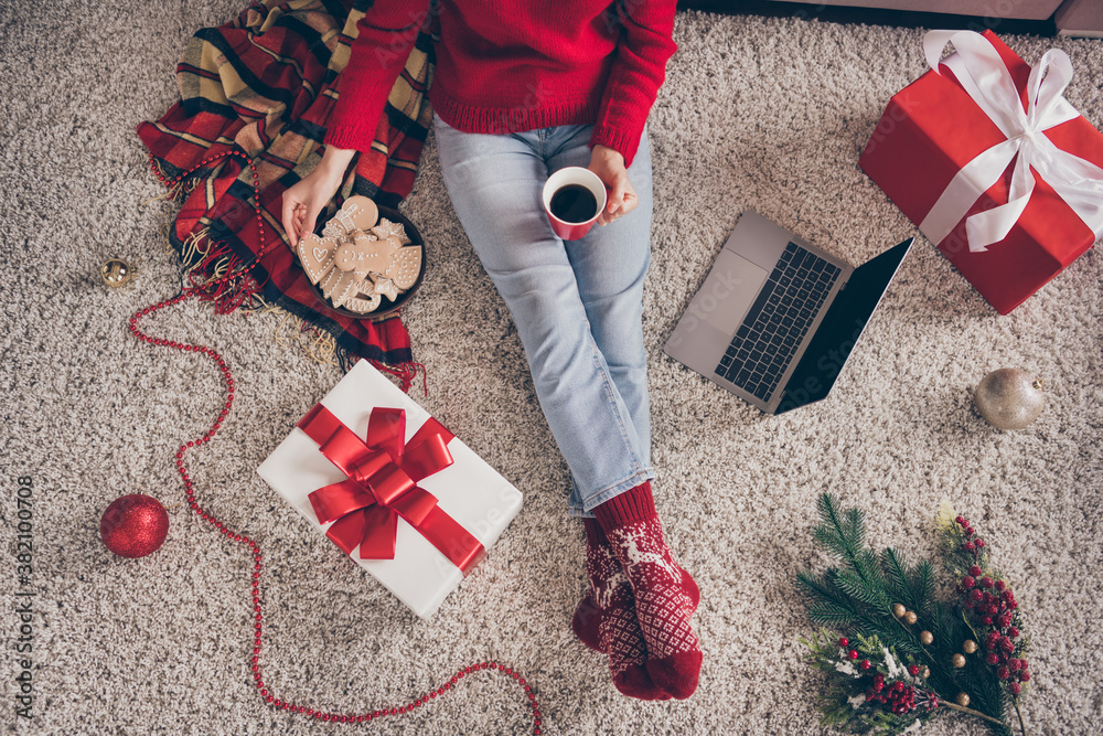 Poster high angle view cropped photo of young woman sit carpet netbook hold cup cookies wear red sweater so