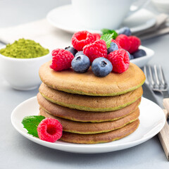 Matcha pancakes served blueberry and raspberry on white plate, square format
