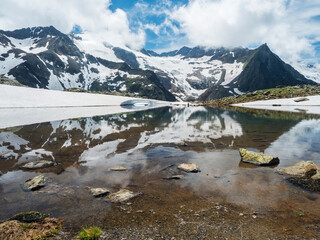 Fototapeta na wymiar Beautiful glacial lake with springs from melting ice glacier with sharp snow-capped mountain peaks reflecting on water surface. Tyrol, Stubai Alps, Austria, summer sunny day