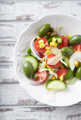 Healthy Salad Green Olives, Baby Spinach, Cucumber, Cherry Tomatoes and Capers. Bright wooden background. Top view. Close up.