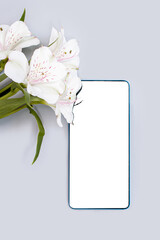 smartphone with a place to insert images next to flowers on a gray background