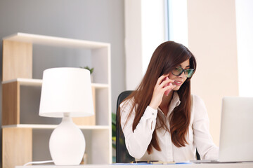 young woman taking notes while talking on cell phone.