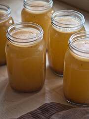 Home made bone broth in glass jars on kitchen table. Natural light.
