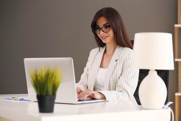 Beautiful business woman uses a laptop and smiles while working in the office