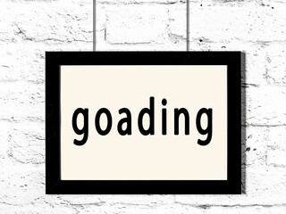 Black frame hanging on white brick wall with inscription goading