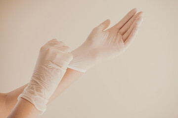 Woman hands putting glove for protect virus, Wearing a glove for safety concept. Hands with white sterile gloves.