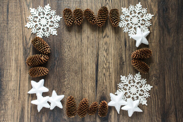 Christmas frame made of snowflakes and cones on a dark wooden background. Christmas, winter concept. Flat lay, top view.