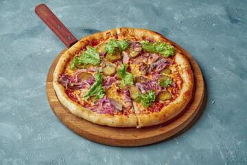 Italian pizza with beef, red onion, pickled cucumber and cheese on wood board on gray background