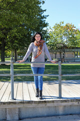 Smiling young woman standing in the warm autumn sun on a boardwalk