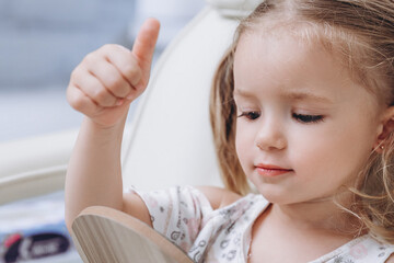 Portrait of a little girl wearing a medical cap sitting on a medical chair in a hospital, dentist or beauty salon