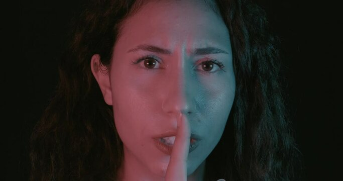 An young beautiful woman is shushing, mute point or stop with his gestures. Ssh concept, calm and relax.