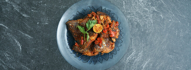 Homemade fried parrot fish with chilli is asian culinary food, served on a stone pad