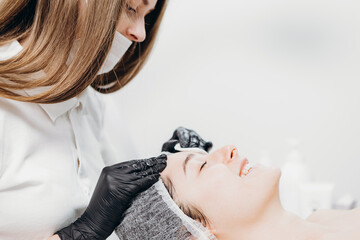 Young woman having spa procedure on her face. Woman lying on spa table and cosmetologist applying...