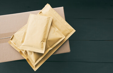 Four different size of paper envelopes and cardboard box on the wooden table