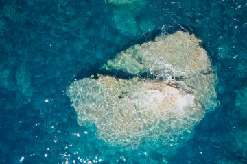 Aerial view of sea waves and fantastic Rocky coast, Italy. Clear amazing azure colour sea water with granite rocks in beach, Italy. Rock and sea. Stone rock close up in the sea water.