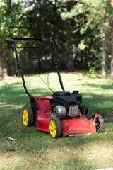 Obraz premium Red lawn mower on a green lawn on a sunny day