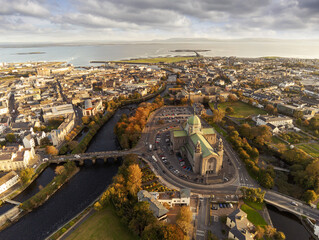 Galway Cathedral building at sunset. Aerial drone view, Warm light, Galway town, Ireland, Popular landmark. Cloudy sky. - obrazy, fototapety, plakaty