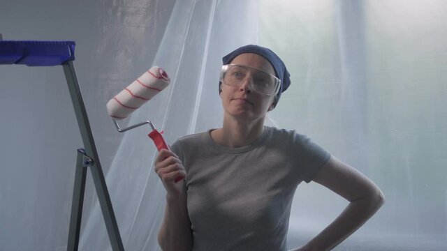 Portrait of a woman with a roller in her hand, making repairs in an apartment
