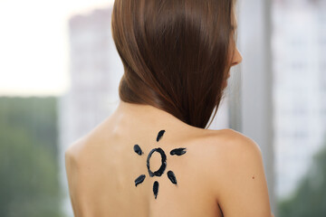 Fototapeta na wymiar Woman with sunscreen on her back on a light background