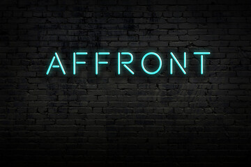 Neon sign. Word affront against brick wall. Night view