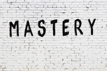 Inscription mastery painted on white brick wall