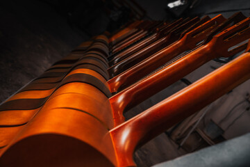 Acoustic guitars stand in rows. Close up of guitars in a row at workshop, music instrumental...