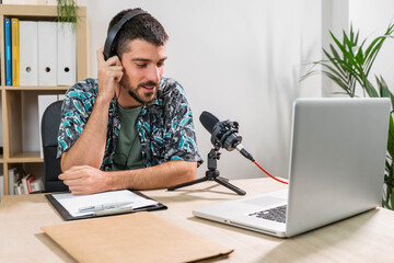 Man working as radio host at radio station sitting in front of microphone. Young radio host...