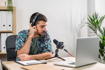 Man working as radio host at radio station sitting in front of microphone. Young radio host...