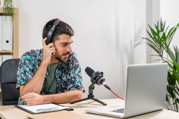 Man working as radio host at radio station sitting in front of microphone. Young radio host...