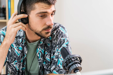 Man working as radio host at radio station sitting in front of microphone. Young radio host...