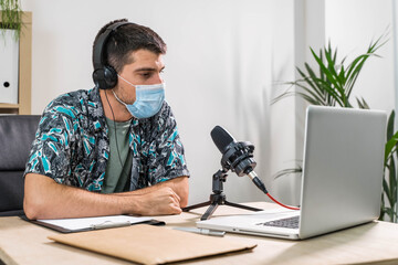 Man working as radio host at radio station sitting in front of microphone. Young radio host...