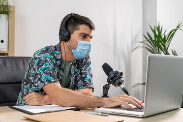 Man working as radio host at radio station sitting in front of microphone. Young radio host...