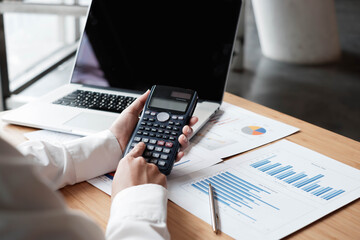 Businessman using calculator for analysis marketing plan, Accountant calculate financial report, computer with graph chart. Business, Finance and Accounting concepts