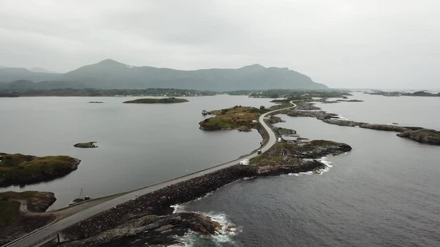 Scenic road trip. Beautiful road surrounded by ocean water. Dark sky, empty road, driving through small islands and on a narrow curvy road.