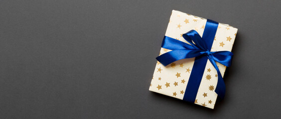 wrapped Christmas or other holiday handmade present in paper with blue ribbon on black background....