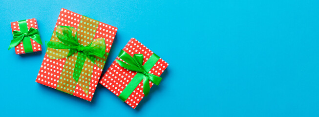 Fototapeta premium Gift box with green bow for Christmas or New Year day on blue background, top view