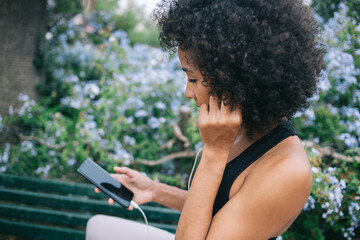 Black woman in park chatting on social media on smartphone
