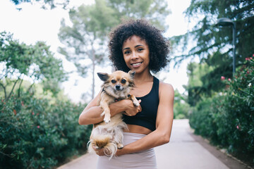 Obraz premium Happy ethnic woman hugging cute Chihuahua dog