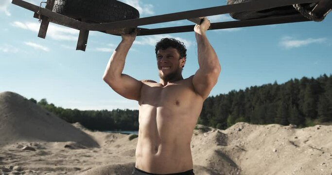 Young athlete trains shoulders with heavy weight armature outdoor. Concept of motivation and sports nutrition